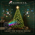 A lit Christmas tree with warm white string lights and a star, beside the snowflake projector casting patterns across the walls